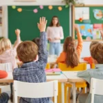 alunos com a mao levantada em sala de aula