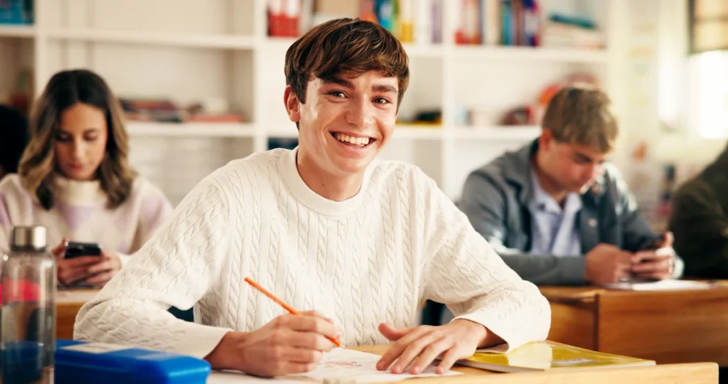 aluno em sala de aula sorrindo para a foto