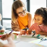 professora ajudando aluna na carteira da sala de aula