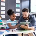 professor ajudando aluna com tablet em sala de aula